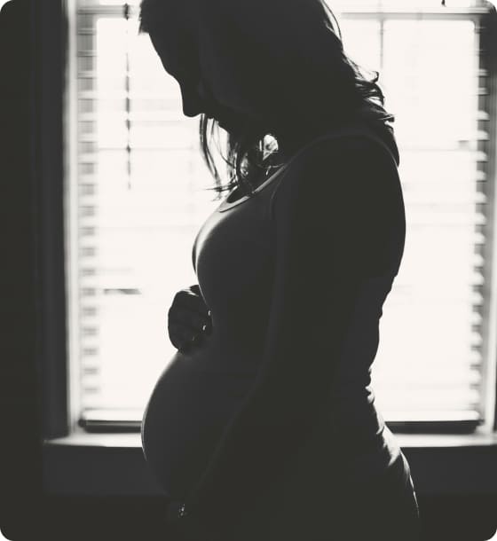 Black and white silhouette photo of a heavily pregnant woman holding her belly