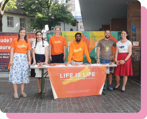 A group of ProLife Europe members at an outreach event, at their stand featuring a long table and a "Life is Life" banner