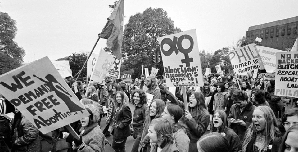 A black and white photo taken in the past at a protest march advocating for abortion rights